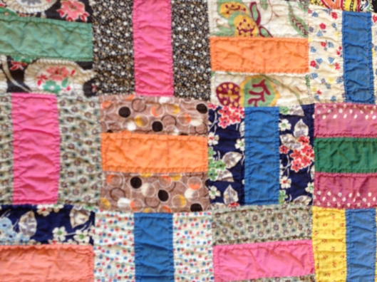 Detail of Basketweave quilt showing a collection of fabrics both plains and patterned.